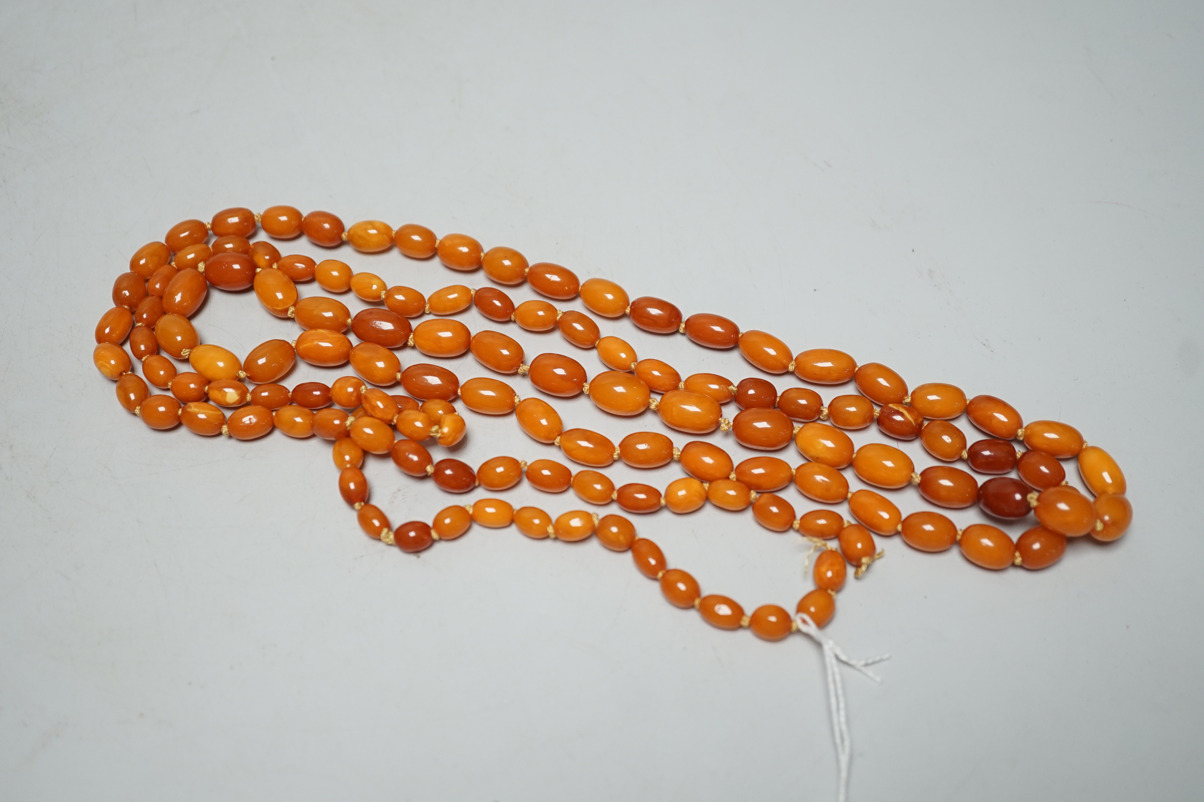A long single strand graduated oval amber bead necklace(string broken), 142cm, gross weight 51 grams.